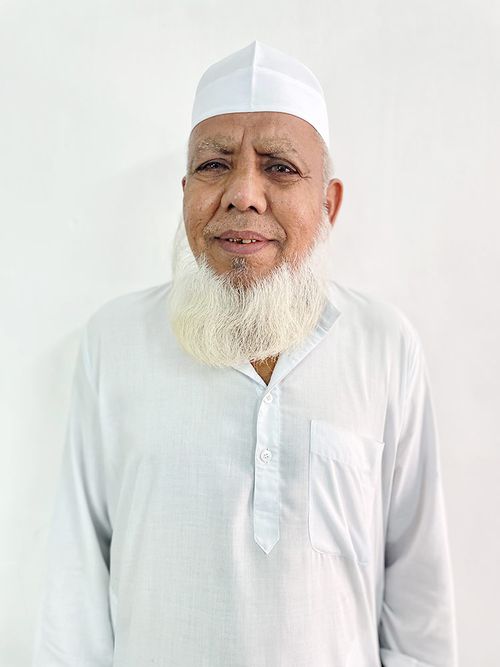 Portrait of a man with brown hair and glasses on a flat gray background.